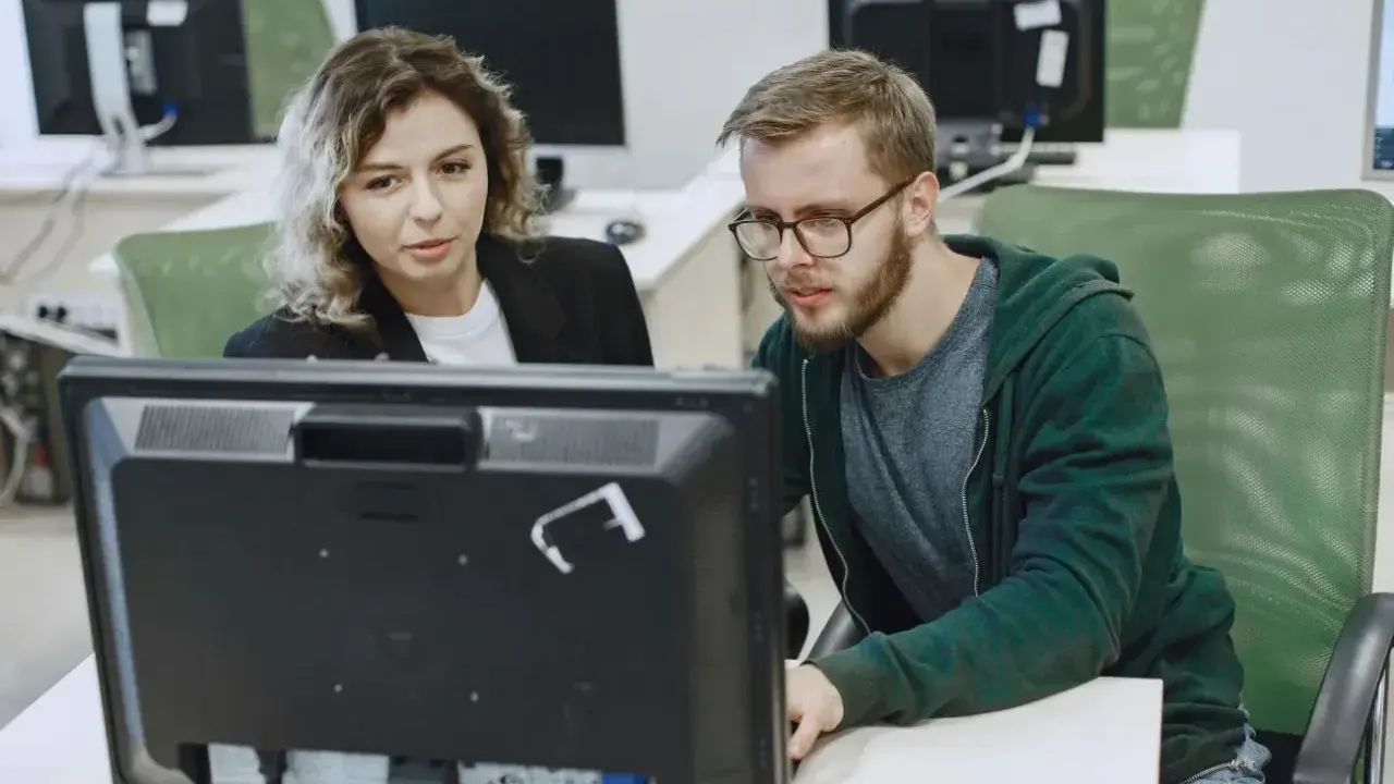 Kobieta i mężczyzna analizują dane na monitorze, dbając o zapewnienie jakości.