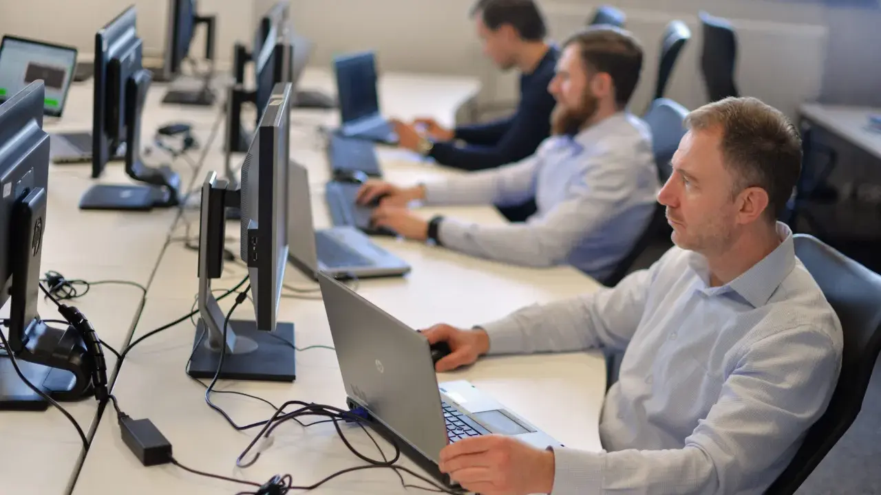 Zespół pracuje nad **static testing**, skupiony na ekranach komputerów w biurze.