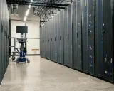Rzędy serwerów w centrum danych. Mobilny wózek z monitorem i krzesłem czeka na technika w tym nowoczesnym środowisku produkcyjnym.