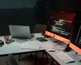Biurko z komputerami i kodem na ekranach, przygotowane do **mutation testing**. Widać części komputerów i dyski.