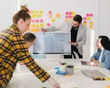 Zespół omawia projekty na monitorze, na ścianie kolorowe karteczki. W tle widać logo ireb cpre foundation.