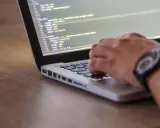 Ręce programisty piszącego kod na laptopie. Tester stron internetowych sprawdza poprawność wyświetlania elementów.