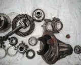 Rozłożony mechanizm różnicowy, widoczne koła zębate, łożyska i obudowa. Może to być wada usterka lub przygotowanie do naprawy.