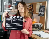Kobieta z klapsem filmowym, tło z plakatami filmowymi i maszyną do pisania. To świetny test case example dla twórców filmowych.