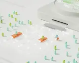 Junior QA engineer testuje grę planszową z kolorowymi pionkami i przezroczystymi elementami.