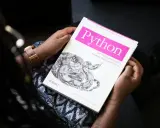 Osoba trzyma książkę "Python for Unix and Linux System Administration". To świetna lektura do testowania oprogramowania i nauki Pythona.