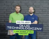 Dwóch mężczyzn na tle ceglanej ściany. Jeden w zielonej koszulce, drugi w niebieskiej. Na środku napis: "Co to jest Dług technologiczny i jak sobie z nim radzić".