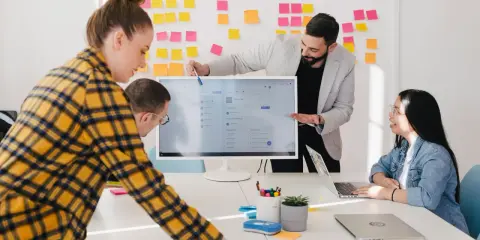 Zespół omawia projekty na monitorze, na ścianie kolorowe karteczki. W tle widać logo ireb cpre foundation.