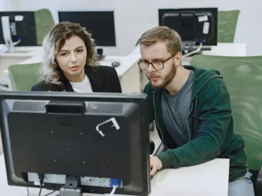 Kobieta i mężczyzna analizują dane na monitorze, dbając o zapewnienie jakości.
