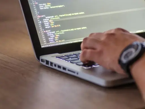 Ręce programisty piszącego kod na laptopie. Tester stron internetowych sprawdza poprawność wyświetlania elementów.