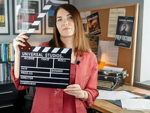 Kobieta z klapsem filmowym, tło z plakatami filmowymi i maszyną do pisania. To świetny test case example dla twórców filmowych.