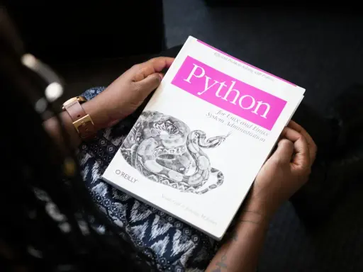 Osoba trzyma książkę "Python for Unix and Linux System Administration". To świetna lektura do testowania oprogramowania i nauki Pythona.