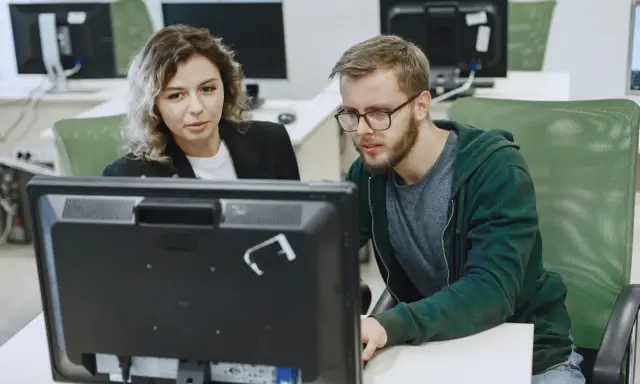 Kobieta i mężczyzna analizują dane na monitorze, dbając o zapewnienie jakości.