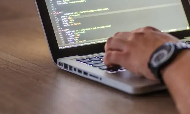 Ręce programisty piszącego kod na laptopie. Tester stron internetowych sprawdza poprawność wyświetlania elementów.