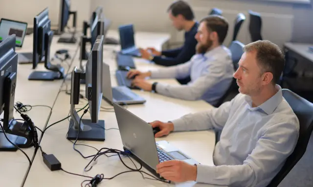Zespół pracuje nad **static testing**, skupiony na ekranach komputerów w biurze.