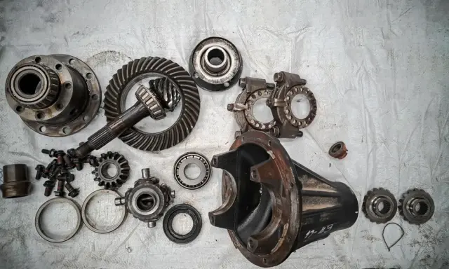 Rozłożony mechanizm różnicowy, widoczne koła zębate, łożyska i obudowa. Może to być wada usterka lub przygotowanie do naprawy.