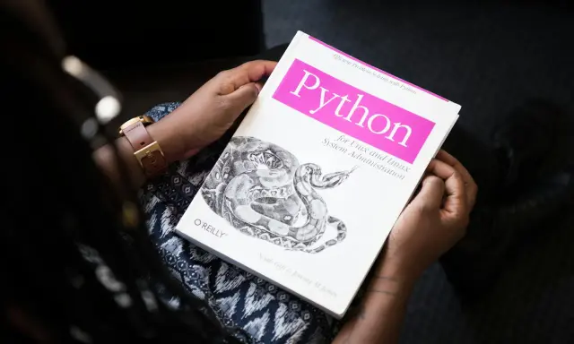 Osoba trzyma książkę "Python for Unix and Linux System Administration". To świetna lektura do testowania oprogramowania i nauki Pythona.